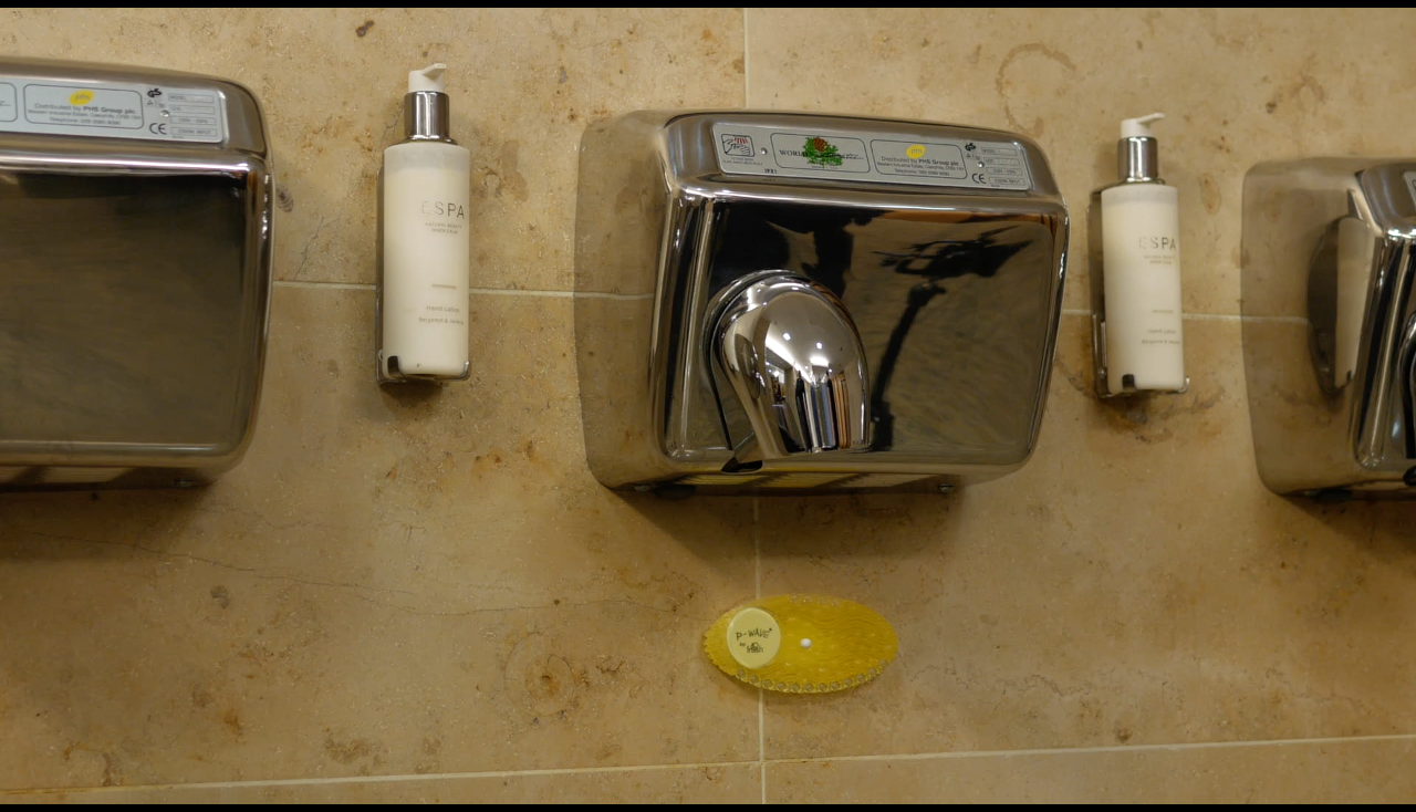 An Image showing a yellow Citrus P-Wave Curve installed underneath a hand dryer in a washroom