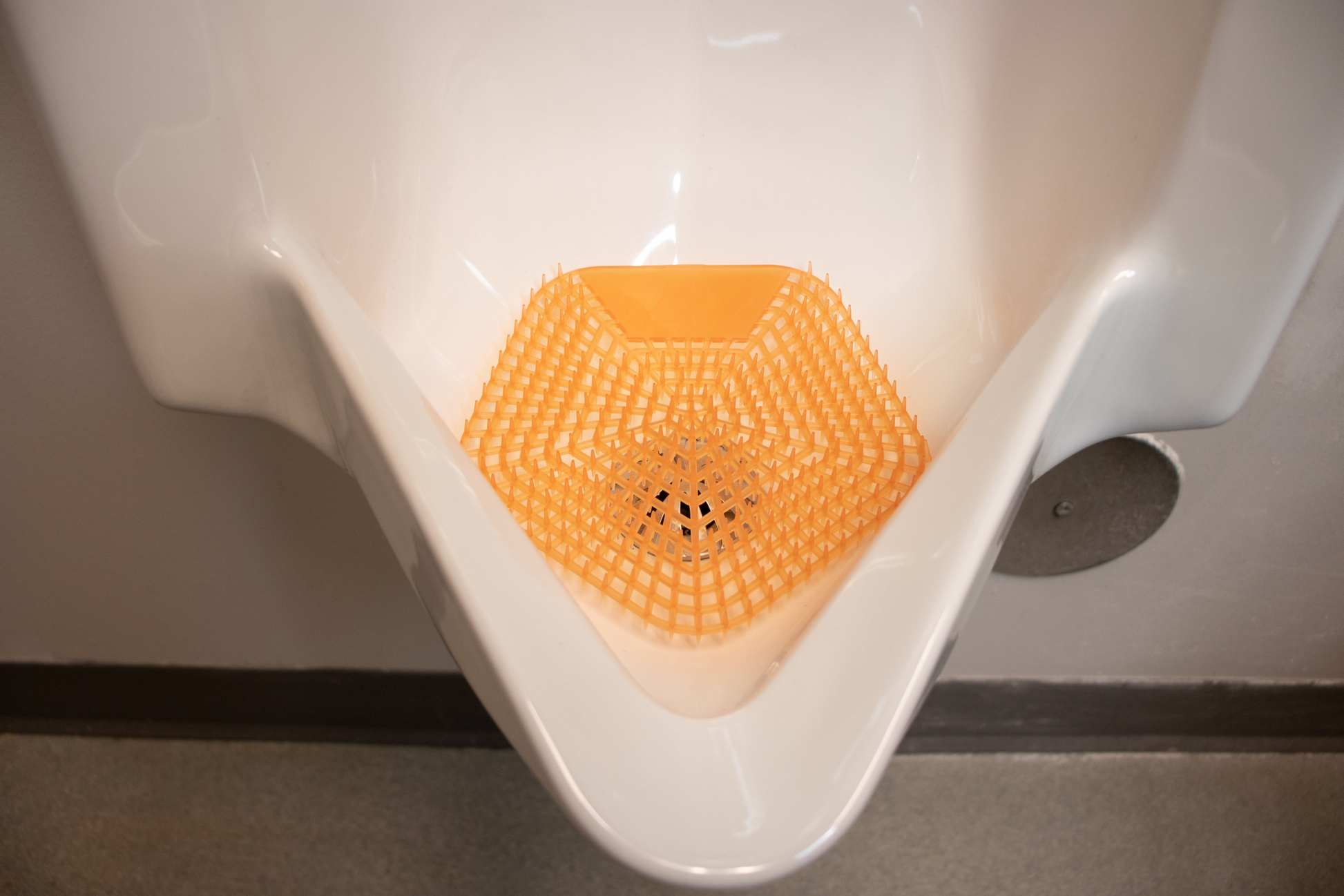 An image of the WCBasix Mango Mist (Orange colour) in a white urinal