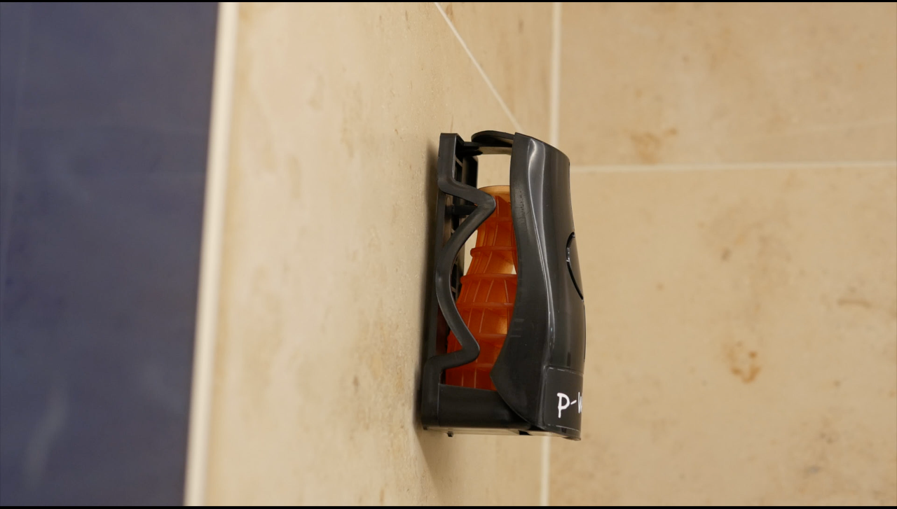 Side view image of a Black Eco Air dispenser installed on a wall, with a Mango refill inside